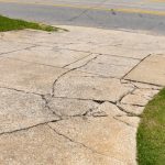 Residential concrete driveway showing recurring cracks caused by sub-base movement and environmental exposure, illustrating driveway cement crack repair challenges.