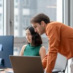 A business leader overwhelmed with decisions while a team waits, illustrating a leadership bottleneck in a modern workplace.