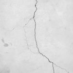 Engineer inspecting fire-damaged concrete structure showing spalling, cracking, and surface deterioration during structural assessment.